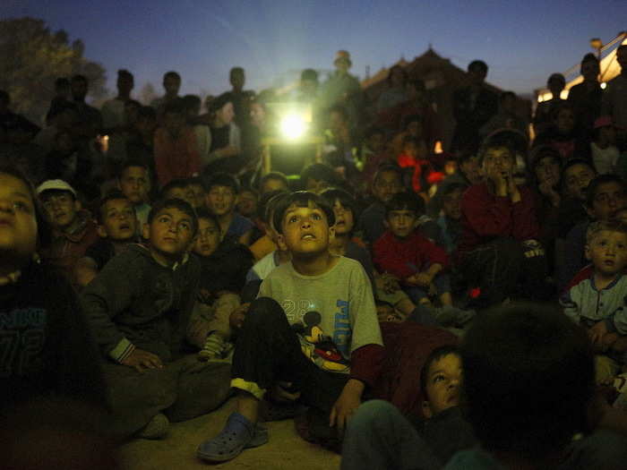 Children at the Greek-Macedonian border, near the village of Idomeni, watched a cartoon movie, screened at a makeshift camp for migrants and refugees.