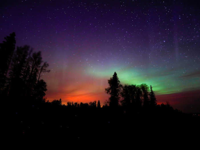 Wildfires glowed underneath The Northern Lights near Fort McMurray, Alberta, Canada.