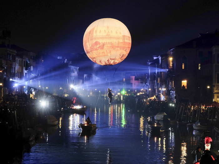 A masked reveller hung from an inflatable balloon during the first day of the carnival in Venice, Italy.