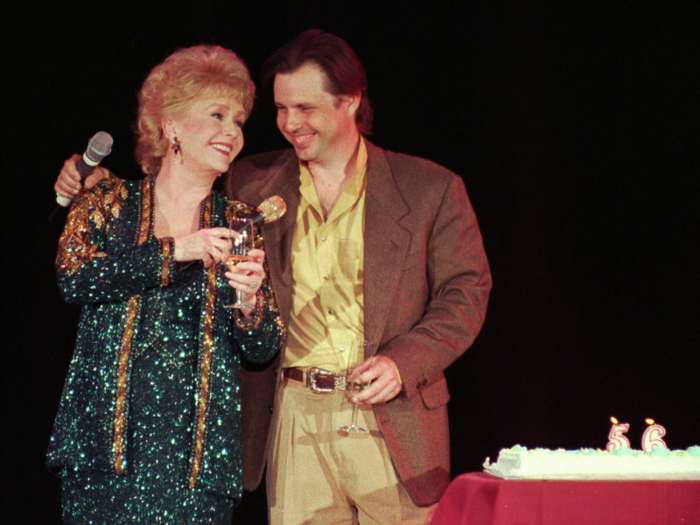 Reynolds celebrates her 65th birthday on stage as Todd Fisher presents her with a cake following her evening variety show on April 1, 1997. Reynolds had a busy 64th year, starring in the critically acclaimed Albert Brooks film "Mother," as well as opening her new variety show.