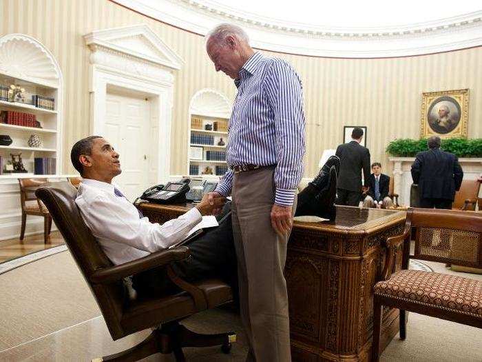 Obama and Biden shake hands in the Oval Office following a phone call with House Speaker John Boehner securing a bipartisan deal to reduce the nation