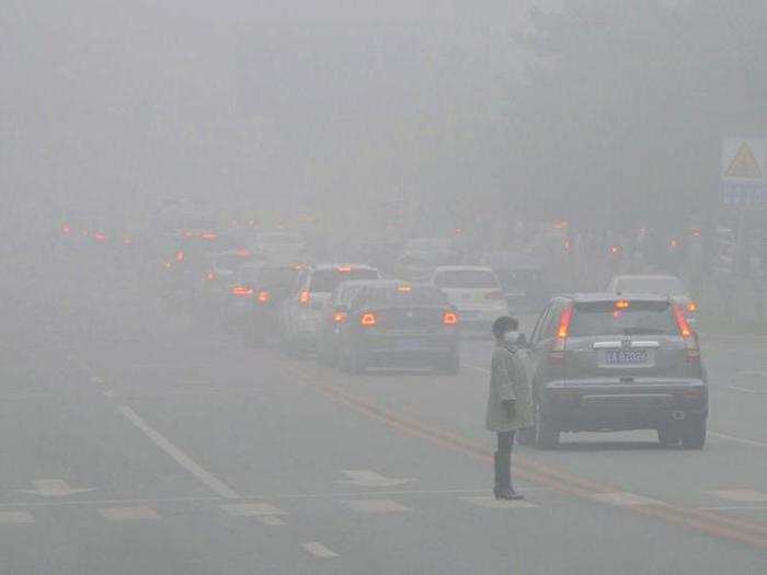 A woman walks across the street during a particularly smoggy day in Changchun.