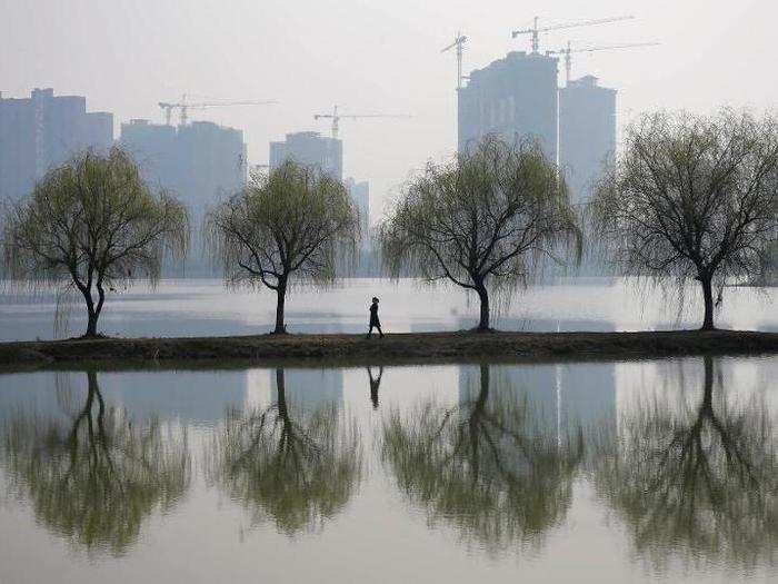 A woman strolls through polluted air in front of a construction site of a residential compound in Wuhan.