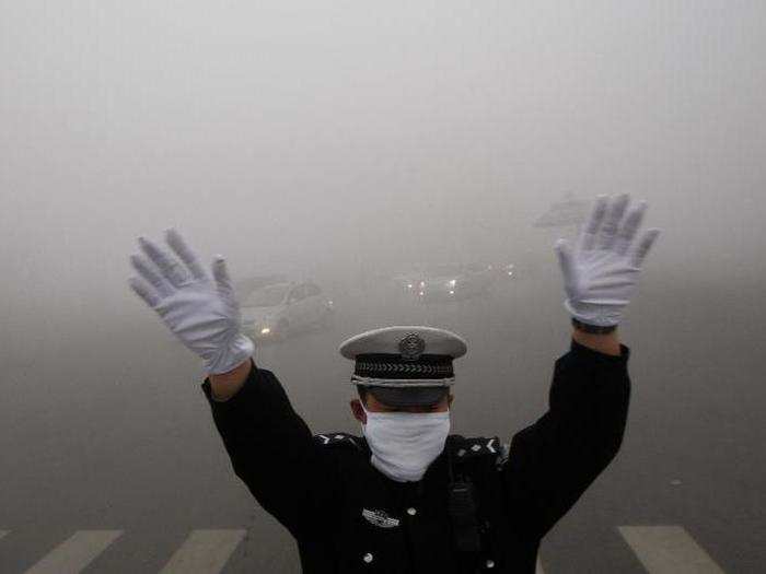 In Harbin, a traffic policeman has to help navigate commuters since they can barely make out the headlights in front of them.