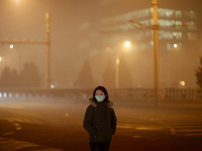 A woman wears a mask on a polluted evening.