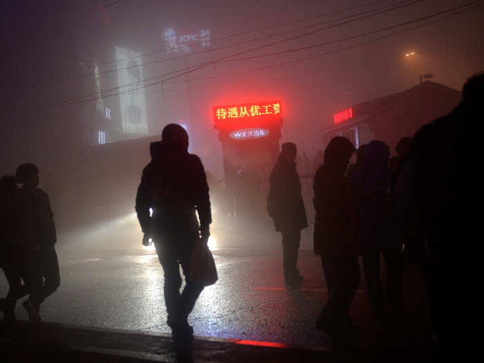 People are seen on the street in smog during a polluted day in Shenyang, Liaoning province.