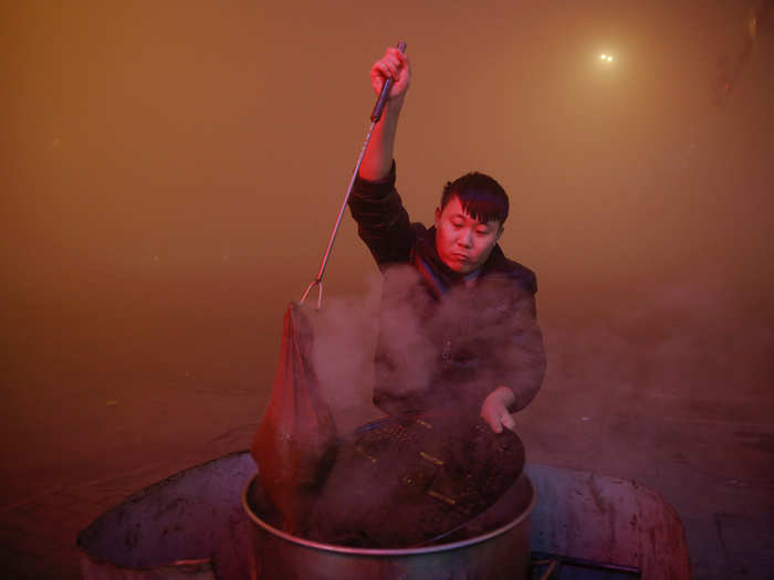 A man cooks in open air during a "red alert" day in Hebei province.