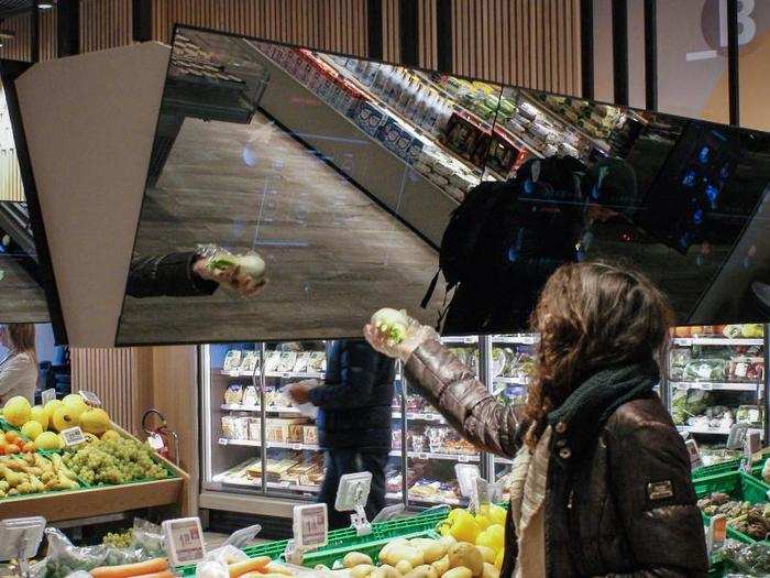 Above the produce, there are long reflective screens.