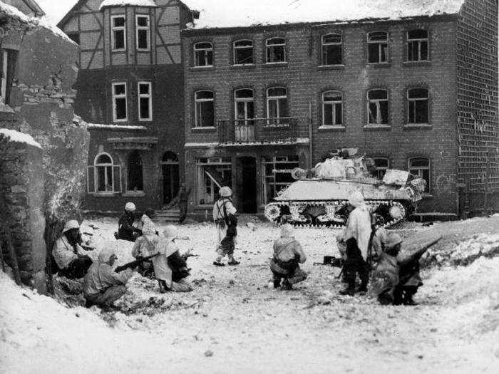 Troops of the American 7th Armored division are on the look-out for snipers in the streets of Saint Vith, Belgium, on January 23, 1945, during the Battle of the Bulge in World War II.