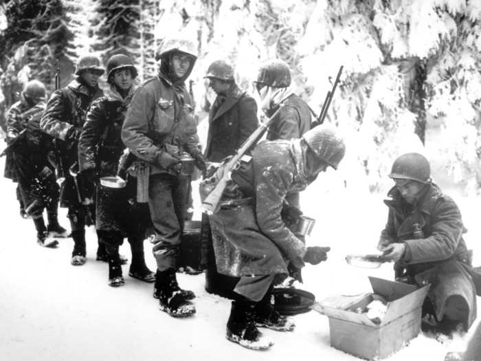 In this image provided by the US Army, soldiers of the 347th US Infantry in heavy winter gear halt their advance to La Roche, Belgium, for a short meal, January 13, 1945.