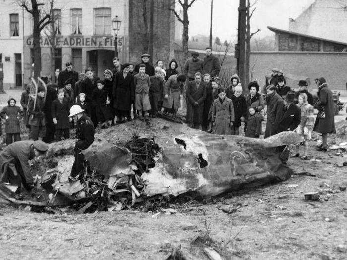 Brussels residents view the wreckage of a FW 190 brought down by a Spitfire on the outskirts of the city. A white-helmeted Belgian policeman guards the wreckage, which is being examined by an RAF officer in Belgium on January 4, 1945.