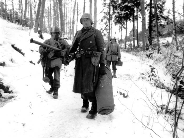 American infantrymen of the 290th Regiment, armed with rifles and bazookas, move through fresh snowfall in a forest near Amonines, Belgium, on January 4, 1945.