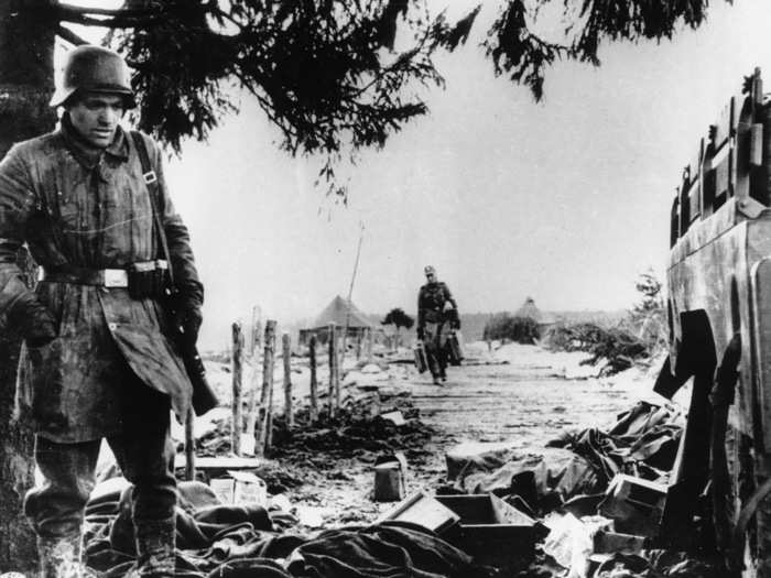 During the German counteroffensive in the Ardennes region, a German soldier looks through American ration boxes and uniforms, somewhere in the Belgium-Luxembourg salient, on January 3, 1945.