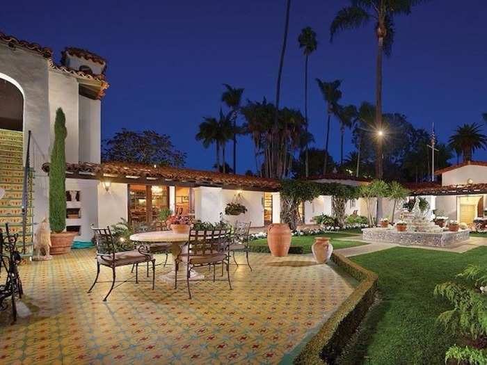 White stucco walls, hand-painted tiles, and wrought-iron detailing are a few of the features that make the home pop against its surrounding greenery.