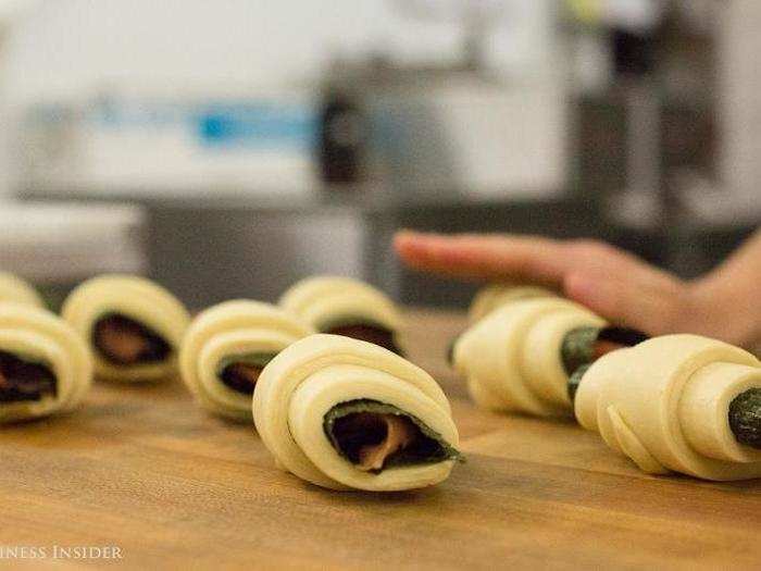 The croissants get a sprinkling of salt, sesame seeds, and crumbled seaweed. They bake for about 20 minutes until they turn "poofy" and golden brown.