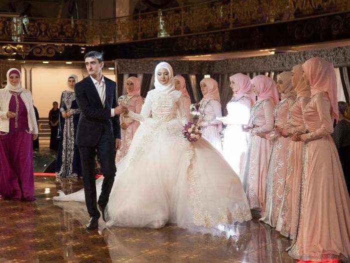 In Chechnya a dress code that emphasizes modesty is strictly enforced. Brides wear white gowns that cover them head to toe. Metal fasteners adorn outfit