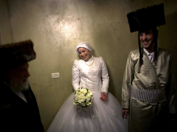 In keeping with the Jewish tradition of modesty, the ultra-Orthodox bride wears a loose-fitting gown that covers everything but her face and hands. A lacy skirt grazes the floor.