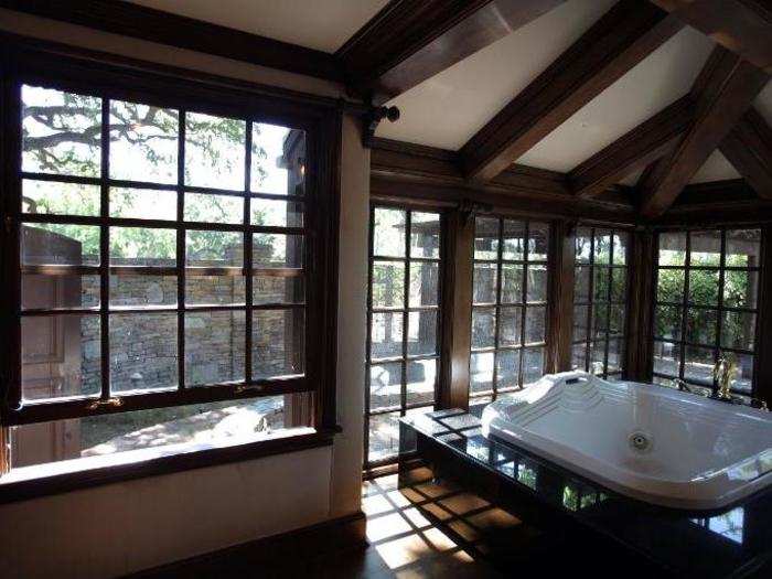 A large Jacuzzi bath is situated against the windows in the master bathroom.