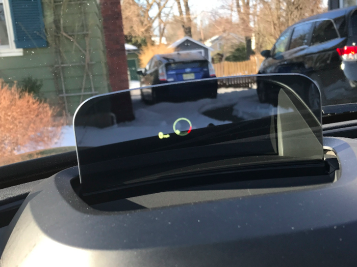 A head-up display rises from the dashboard and projects speed and a tachometer.