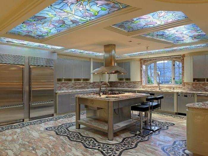 The kitchen sits under stained-glass skylights. It has plenty of custom touches, like stone flooring, two steel refrigerators, and a center island-mounted range and hood.