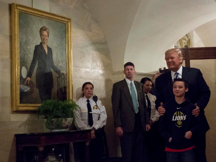 Trump surprises a White House tour and poses with a young visitor in front of a portrait of Hillary Clinton