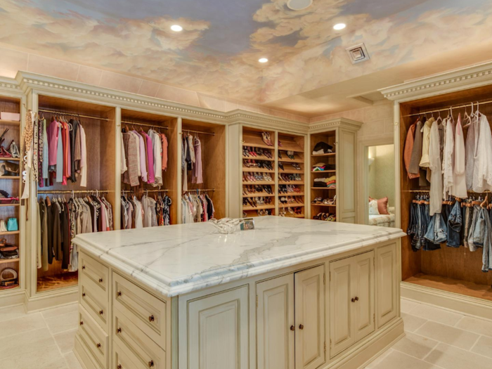 Next to the bathroom is a large dressing room with built-in cupboards and a marble-topped island in the center. There are custom-built racks for shoes and handbags.