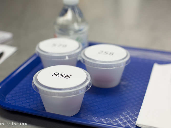A typical taste-test tray includes several sample cups containing bite-sized pieces of vegetables, a bottled water, a "spit cup," and a clicker for submitting a rating per sample.
