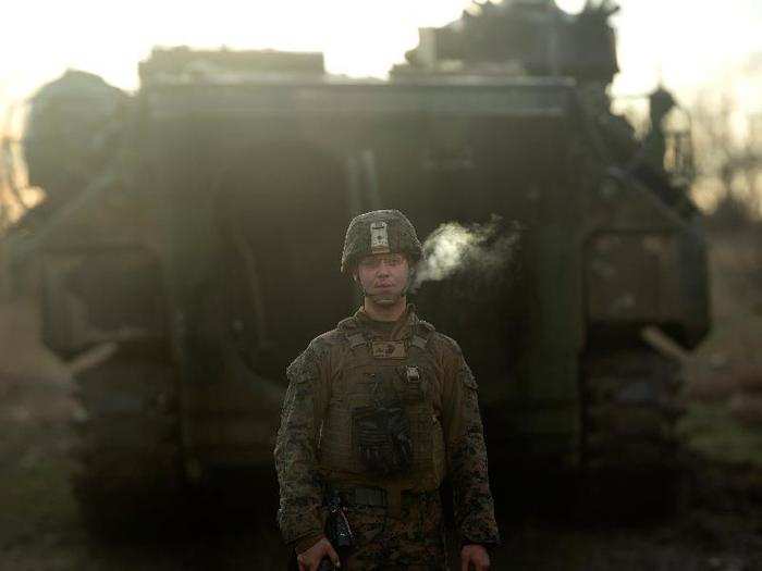 US Marine Lance Cpl. Brandon Hecht, an assault amphibian crewman, smokes a cigarette in front of an assault amphibious vehicle, which he