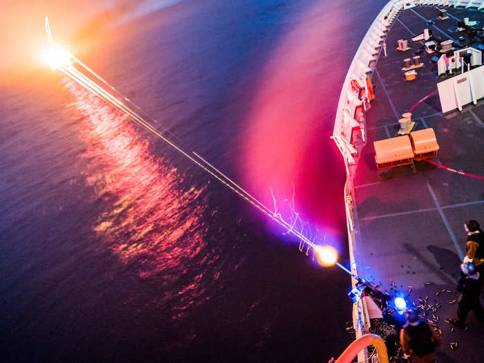 US Coast Guard members practice shooting a 50-caliber machine gun at night during a deployment aboard Coast Guard Cutter Stratton.