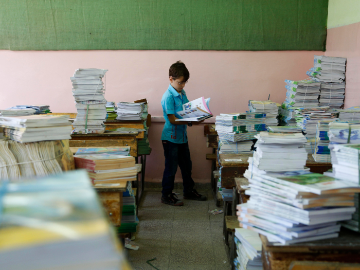 Syria: A Syrian child inspects a book on his first day back to school in a suburb of Damascus.