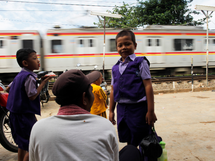 Indonesia: Students wait for a train to pass as they make their journey home after attending the first day of kindergarten in Jakarta.