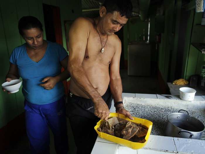 Gonzalo cuts coca paste into pieces ready to sell while his wife observes at their home. Gonzalo says he gets about $900 for a kilo of finished coca paste.