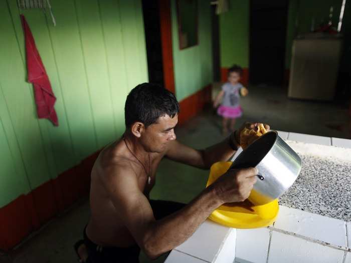 While his granddaughter watches, Gonzalo pours liquid of coca-paste residue after cooking it in his kitchen. Once the yellow paste is cooked to evaporate the chemicals and water content, it