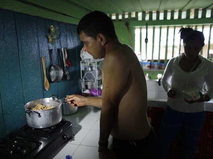 Gonzalo cooks coca paste in the kitchen of his house as his daughter-in-law Valeria looks on. This last step is called "fritada," or "fry-up." The coca paste residue is placed in water and heated until most of the water content is evaporated.