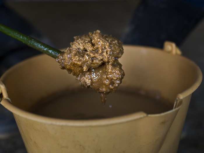 Edgar holds a mixing stick with lumps of solidifying coca paste. The paste is extracted after adding a strong acid into the mix that will further precipitate the alkaloid.