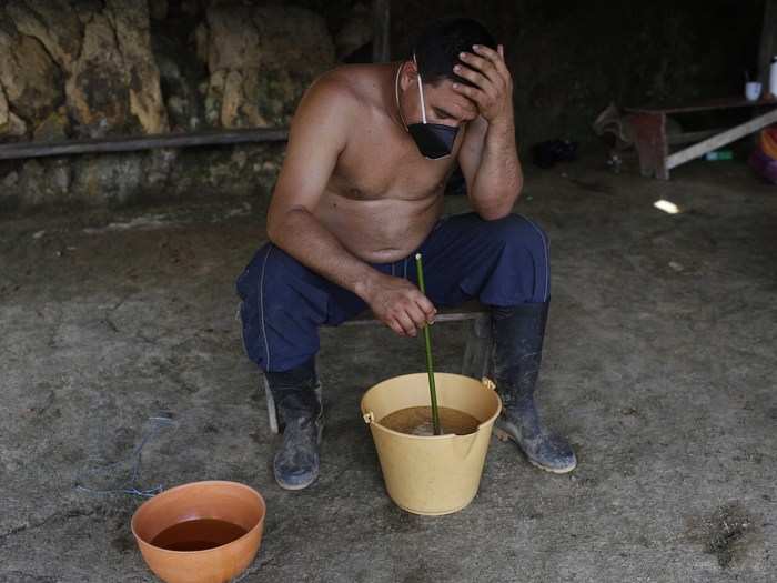 Edgar mixes liquid coca paste with a mask on because it can be hard to breathe amid the noxious fumes that emanate from various buckets marinating the huge mix of leaves.