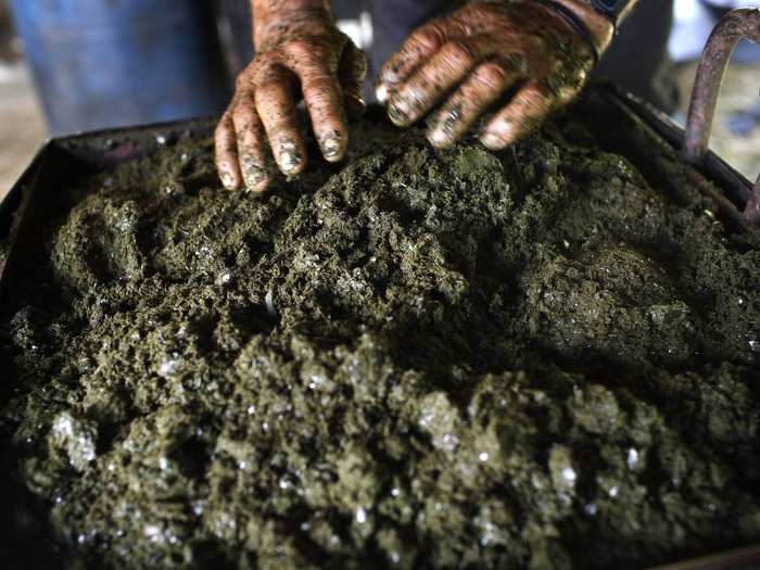 Gonzalo places mulched coca leafs sprinkled with cement and soaked in gasoline into a press as he makes coca paste. The mixture is put into a press so the basic liquid extract of coca paste can be squeezed out.