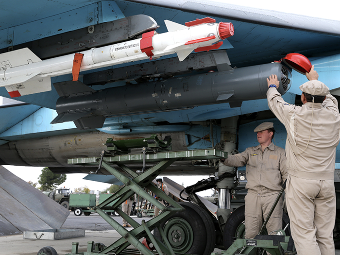 This shows Russian airmen installing precision-guided KAB-500s at the Hmeimim air base. One airman is removing the red cap that protects the sensor during storage and installation. The white ordnance is an air-to-air missile.