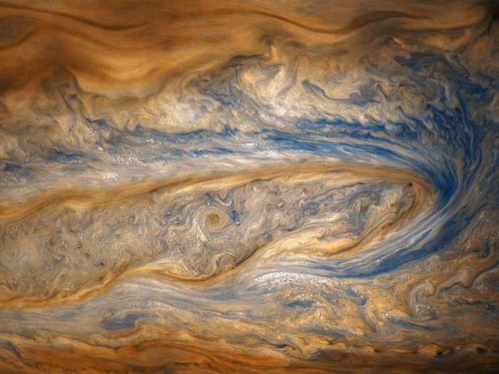 In this older view of Jupiter from the eighth perijove, two cloud bands battle for dominance — one of which contains a swirling storm many times larger than a hurricane on Earth.