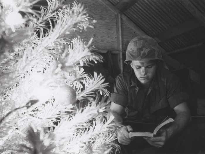 Marine Cpl. Larry Nabb reads next to a Christmas tree at Quang Tri Combat Base, Vietnam, in 1968.