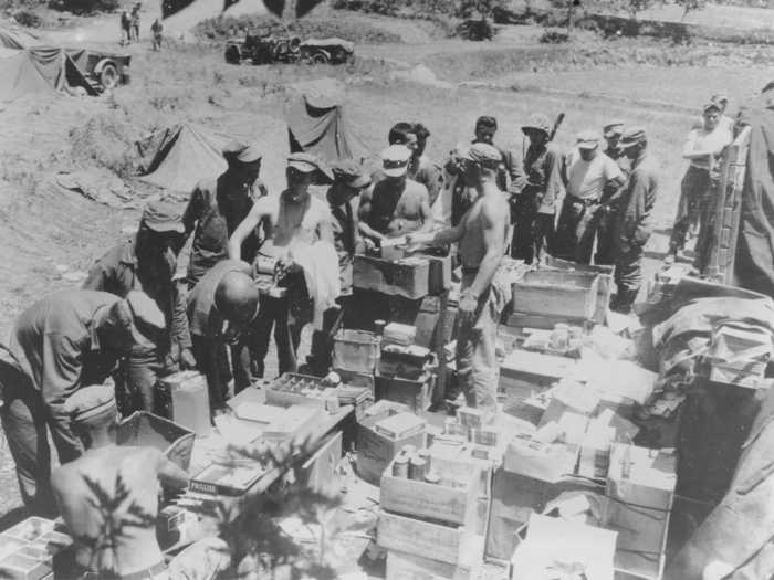 Marines line up at a makeshift Post Exchange in Korea to get comfort items like candy, cigarettes, and soft drinks.