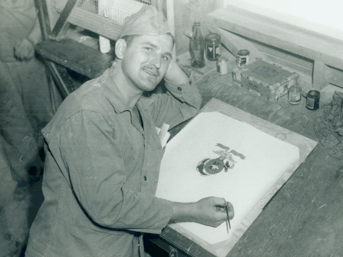 In this 1943 photo, James Wrobel designs the insignia for Marine Fighter Squadron 312. The official Marine Corps emblem has an eagle, a globe, and an anchor. The eagle represents readiness and precision. The globe represents the Corps