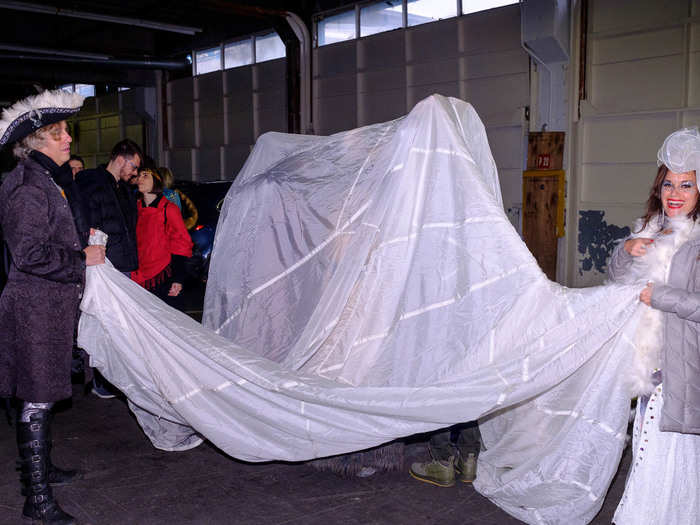 Volunteers were draping the white parachute over partygoers and asking them to do one of several activities, like learning a dance routine, harmonizing a song, or gazing into each other