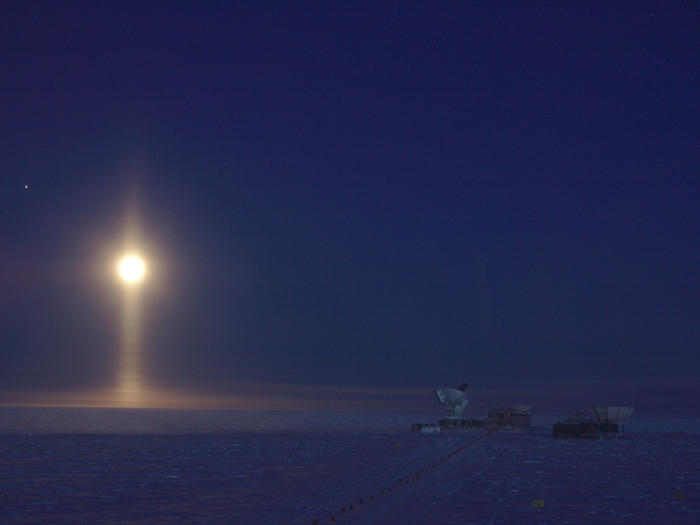 Ice crystals suspended in the atmosphere create the image of a light pillar underneath the moon as seen from the South Pole.