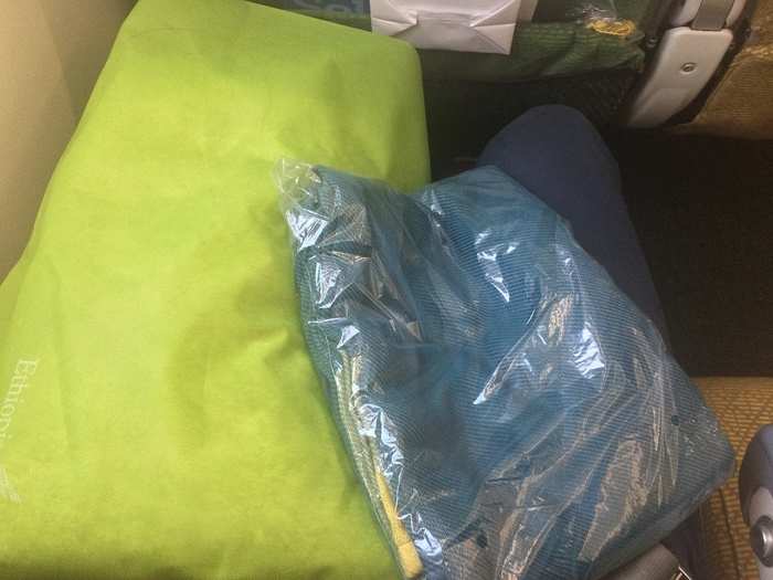 The seat came with some nice in-flight amenities, including a bright green pillow and a teal, Ethiopian-branded throw blanket. The pillow seemed to be made of paper and air. The blanket was surprisingly cozy.