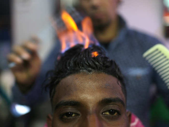 Palestinian barber Ramadan Odwan styles and straightens the hair of a customer with fire at his salon in Rafah, in the southern Gaza Strip.