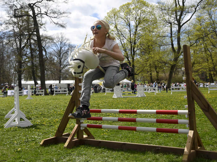 Girl jumps over a hobby horsing fence during a Finland 100 equestrian event in Helsinki, Finland.