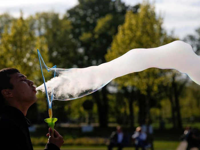 A man blows smoke into a soap bubble at Gorky park in Moscow, Russia.