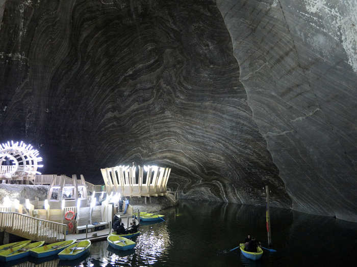 A picture shows a general view of a chamber with an underground lake and boats inside the Salina Turda salt mine in Romania.