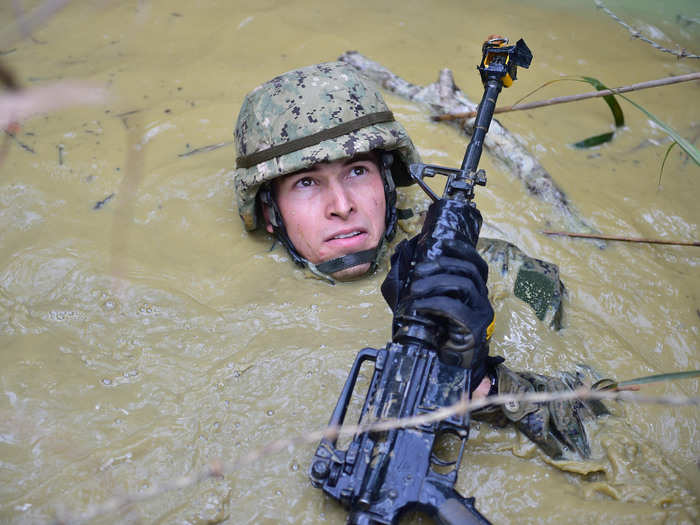 A member of the Naval Mobile Construction Battalion 5 traverses a mud-filled pit while participating in the endurance course at the Jungle Warfare Training Center in Okinawa, Japan on February 17.